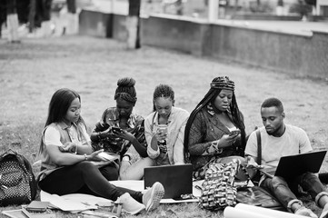 Group of five african college students spending time together on campus at university yard. Black afro friends making with mobile phones. Education theme.