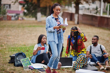Group of five african college students spending time together on campus at university yard. Black afro friends studying. Education theme.