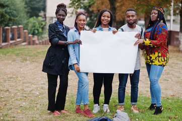 Group of five african college students on campus at university yard hold empty white blank. Free space for your text. Black afro friends studying.