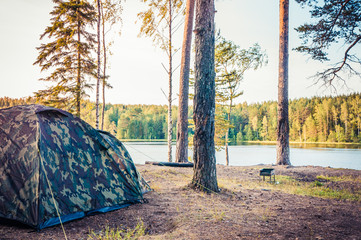 Forest scenery with camping tent on bank of lake