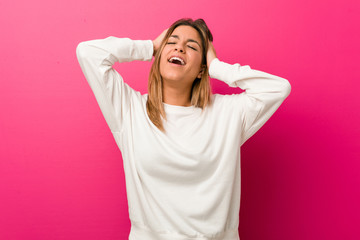 Young authentic charismatic real people woman against a wall laughs joyfully keeping hands on head. Happiness concept.