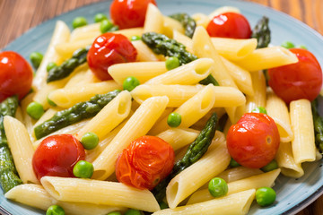 Penne pasta salad with asparagus , tomatoes and peas