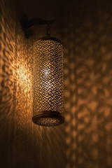 Lit moroccan brass lamp casting beautiful shadows on the wall.