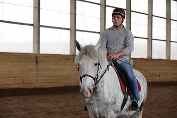 People on a horse training in a wooden arena