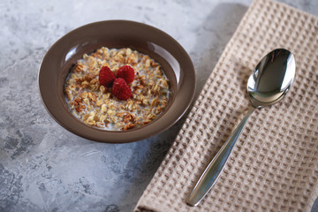 Baked granola with milk and raspberries in a plate. Healthy breakfast. Tasty muesli, snack.