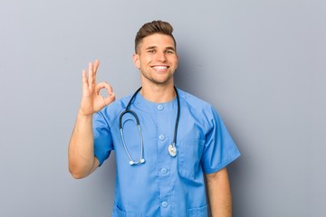 Young nurse man cheerful and confident showing ok gesture.