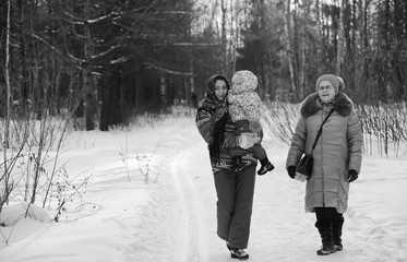 Fototapeta na wymiar Black and white photo of parent holding kid on hands in winter park