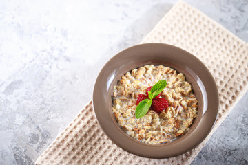 Baked granola with milk and raspberries with mint in a plate. Healthy breakfast. Tasty muesli, snack. top shot