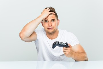 Young man holding a game controller being shocked, she has remembered important meeting. © Asier