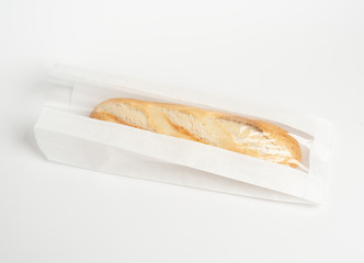 Loaf of fresh baked artisan baguette bread in market paper bag over white background. Top view,...