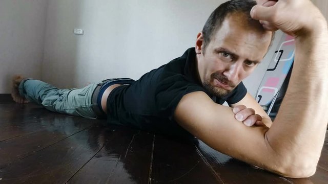 A funny ugly slim man, showing his muscles by flexing them