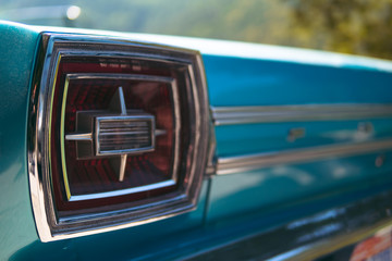 Color detail on the backlight, stop light of a vintage car sky blue color and shiny chrome, selective focus, turquoise, copy space