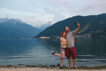 A young couple on the lake take pictures, take selfies, enjoy the views, vacation, relax. couple in love Zell am see in Austria, copy space, selective focus, summer day