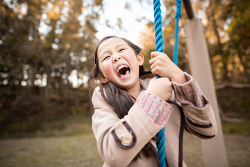 秋の公園で遊ぶ笑顔の女の子