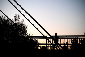 A young man on a metal bridge. Iron bridge with a silhouette of a walking man.