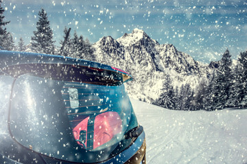 Black big car on a winter snowy road. Landscape of mountains and forest covered with snow and frost. Winter skiing trip. Place for your text or product. Falling snowflakes.