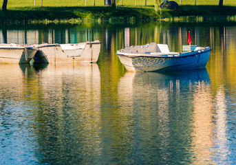 Reflections of boats in a quiet lake in the evening.