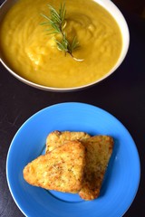 Pumpkin soup and chives with hash browns on dark background