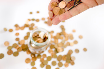 a lot of European coins in hand on a blurred background with a piggy bank and coins