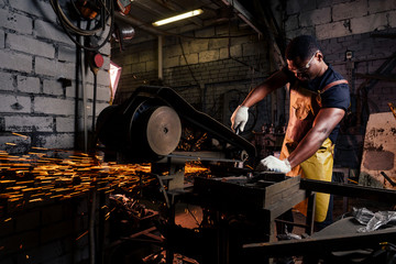 handsome african american blacksmith male worker working in workshop,wearing leather apron