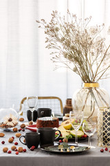 Common dining room table with food, fruits, cake and flowers in vase