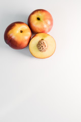 Ripe red, orange and yellow nectarines, peaches, apples on a white table. Tasty bright fruits. Healthy eating. Isolated object.