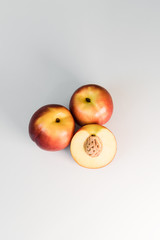 Ripe red, orange and yellow nectarines, peaches, apples on a white table. Tasty bright fruits. Healthy eating. Isolated object.