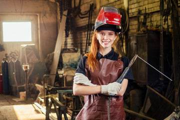 Strong and worthy pretty redhead ginher woman wearing protection helmet and leather apron with...