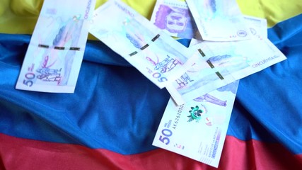 Bitcoins and different denominations of Colombian banknotes falling on the Flag of Colombia - Powered by Adobe