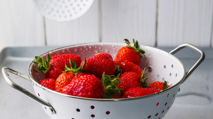 Sieb mit frischen Erdbeeren werden gewaschen mit Wasser unter fließendem Wasser unter dem Wasserhahn