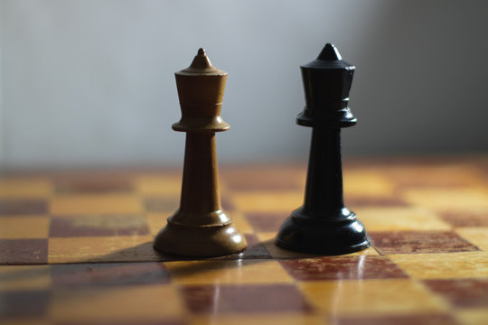 Chess pieces on a chess board in dramatic lighting.