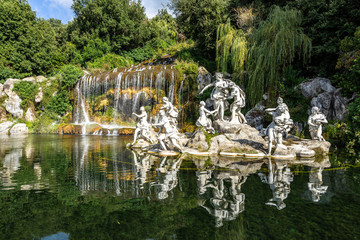 The statues of the Fountain of Diana and Acteon at Caserta Royal Palace reflecting into the waters under the  great waterfall, Campania, Italy - obrazy, fototapety, plakaty