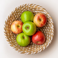 Red and green apples in the basket, at the white table, top view