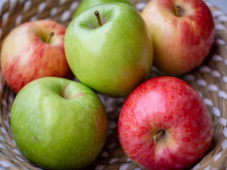 Red and green apples in the basket, closeup