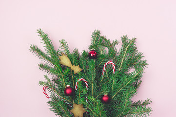 Green Branches Fir Tree With Christmas Decorated With Christmas Candy Canes Red Balls and Gingerbreads Cookies on Pink Paper Background Top View Horizontal Christmas Bouquet