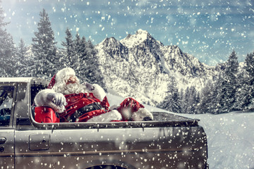 Bearded in red clothes sits on the back of a white truck.Santa distributes gifts for...