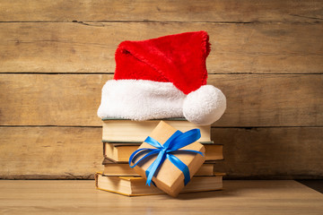 Obraz na płótnie Canvas Pile of books, Santa Claus hat and Gift on a wooden background. Holiday concept, christmas, christmas eve