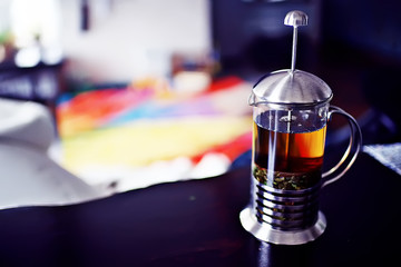 Indian tea / Indian tea concept in a glass teapot against a background of bright carpet in paints of holi, a national Indian drink