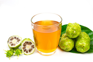 Noni fruit and noni juice in glass isolated on white background.