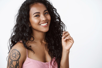 Beauty, wellbeing and women concept. Attractive african-american curly-haired girl with tattoos, clean skin, smiling, laughing coquettish making silly flirty expression, having fun, white background