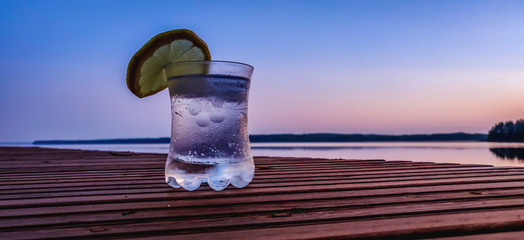 Gin and tonic with ice and lemon on a pier