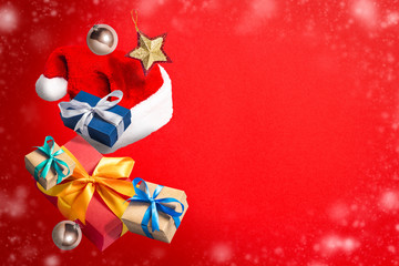 Flying Santa Claus hat, gift box and Christmas decorations on a red background. Holiday concept, christmas. Levitation. Items in the air. Flat lay, top view
