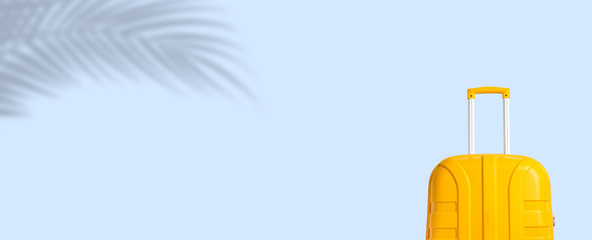 Yellow suitcase under the shadow of palm leaves on a blue background. Travel and vacation concept...