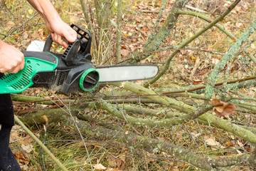 man sawing a log with a chain saw