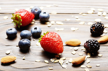 Ripe organic strawberries, blueberries, blackberries almonds and cereal grains on the top of wooden table