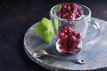 cranberries in sugar in cup with mint. On a dark wooden background