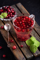 cranberry juice with honey in a cup, cranberries in sugar. On a dark wooden background