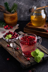 cranberry juice with honey in a cup, cranberries in sugar. On a dark wooden background Vertical