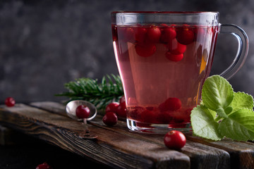 cranberry juice with honey in a cup, cranberries in sugar. On a dark wooden background