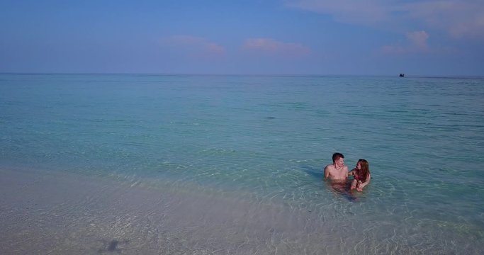 Videography on the tropical beach. Honeymoon and wedding videographer flying a drone above a young couple
